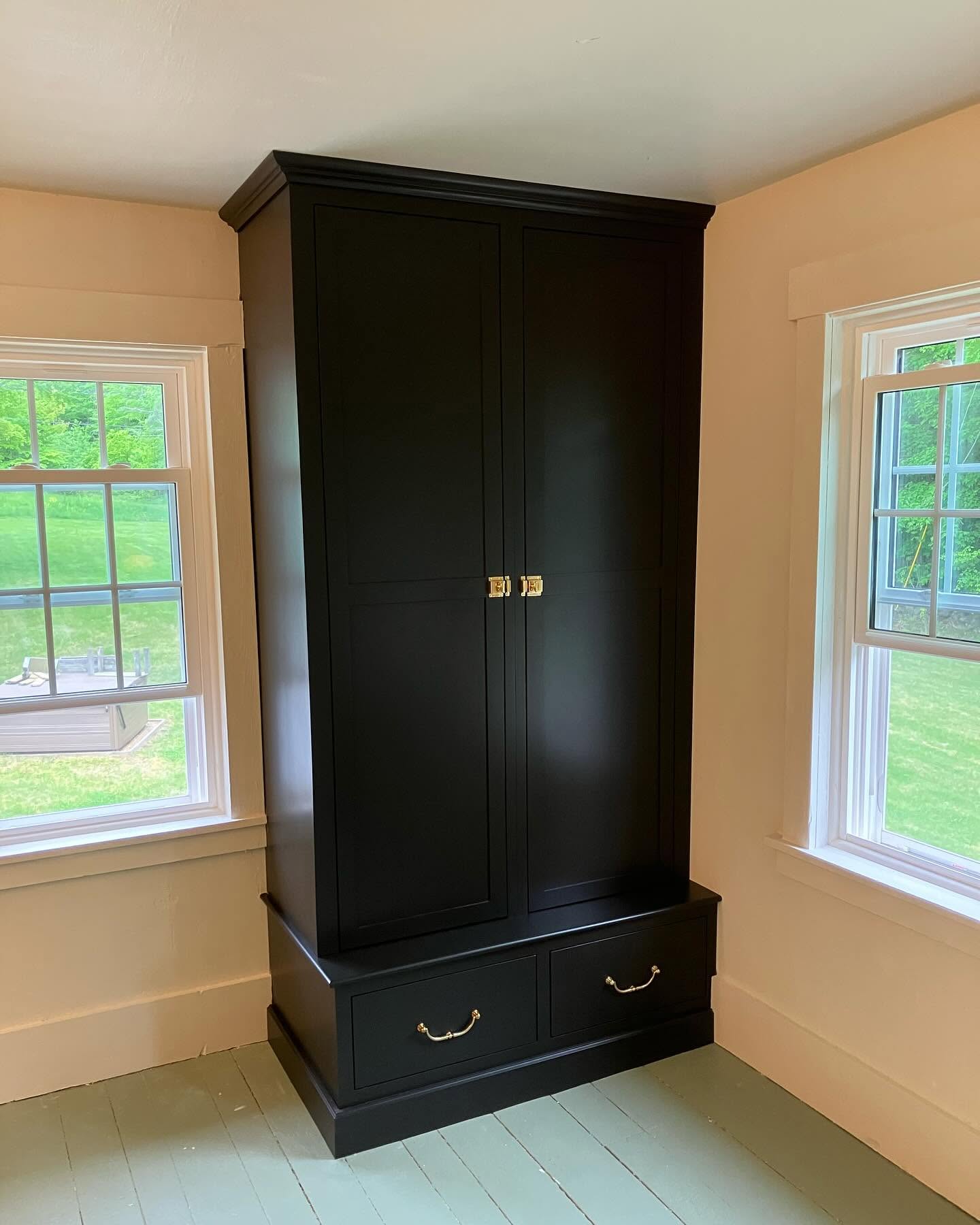 Tall black built-in armoire with brass hardware